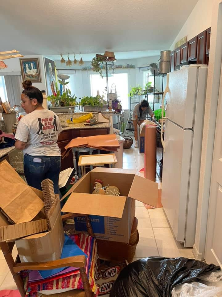 Two people organizing and packing boxes in a bright kitchen during a move