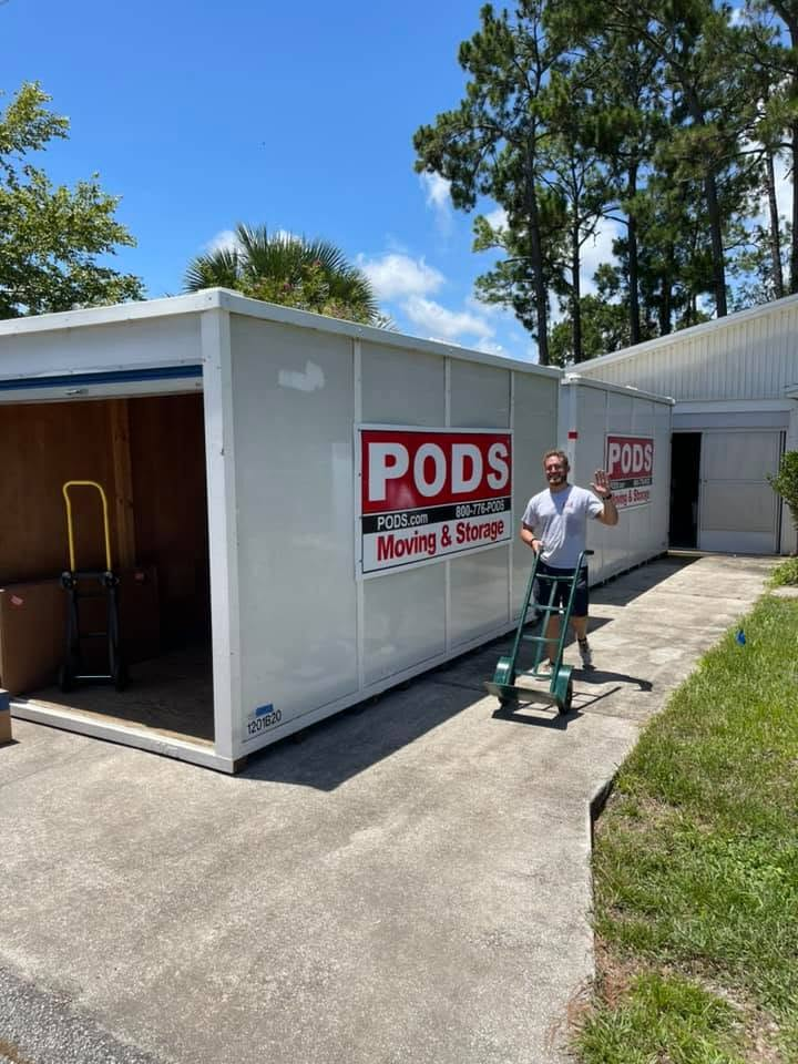 PODS moving and storage container with worker holding dolly on residential driveway